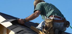 Man repairing shingles on roof