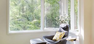 Gray chair by a large window overlooking trees